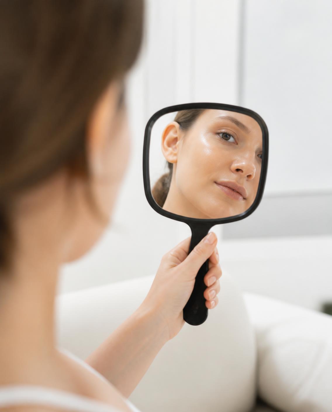 Checking her skin in a hand mirror